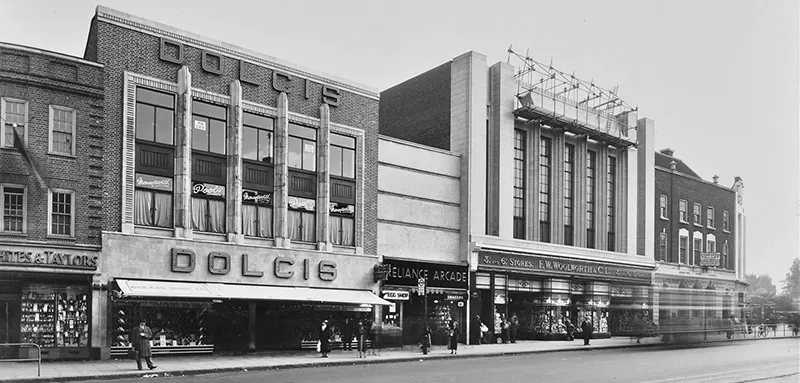 The major redevelopment of the Brixton streetscape and building line, led by F.W. Woolworth nearing completion in November 1937. A new neon sign is being installed at the top of the glazed faience front, which would remain a feature for the next seventy years, until well after Woolworth stores had departed Britain's High Streets for the last time