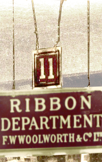 Sandblasted glass signs, with gold lettering and trim painted or stencilled in reverse on the back and then oversprayed with maroon paint guided shoppers to the principal counters, like the popular Ribbons Department A second smaller square sign showed the counter number, which was used to point customers in the right direction when they asked for guidance