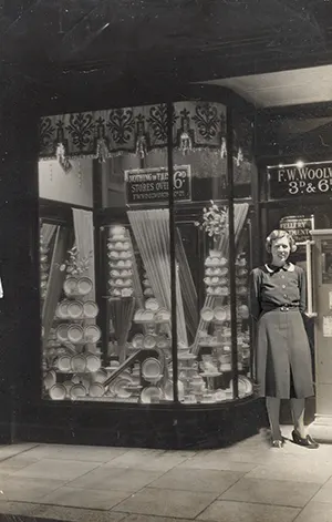 Building on what he had learnt while setting up this displays at his brother's enlarged superstore at Clapham Junction in London, Phil Picot hired Annis Bolsher to be the window dresser to be part of the team at his own first store in Strood, Rochester, Kent. Annis poses for the camera alongside her first display of cups, saucers (3D the pair) and teaplates (2D each) from the main display window to the left of the main entrance. Sharp-eyed viewers may also spot the sign for the jewellery department, which was straight inside the main entrance.